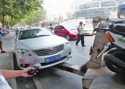 交警將違法停放在緯五路一所學(xué)校門口的車輛拖走