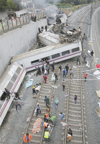 24日，救援人員在西班牙列車脫軌現場。一節車廂被強大的慣性拋上鐵道邊的高臺。