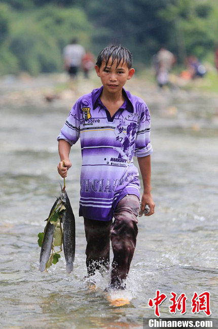 圖為7月9日，一名男孩在鬧魚節活動中抓到了兩條魚。譚凱興 攝