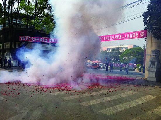 市民在普洱市主干道振興大道的金孔雀交通運(yùn)輸集團(tuán)有限公司門前燃放鞭炮，公司門前掛著“貪腐份子沈培平被查處，罪有應(yīng)得，大快人心。”的條幅