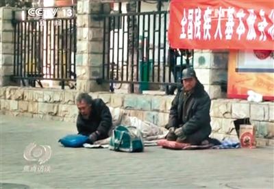 工人體育場北路，兩位乞討者路邊乞討，并輪流扮成“病人”（躺地者）。 央視截圖