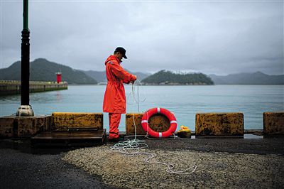 7月6日，韓國珍島，一名海岸警察在港口系救生圈。4月，客輪在珍島近海發生沉船事故后，仍有11人下落不明。