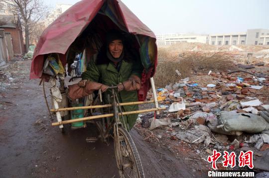 圖為老人走出窩棚，推著三輪車準備出去撿拾廢品。周小云 攝