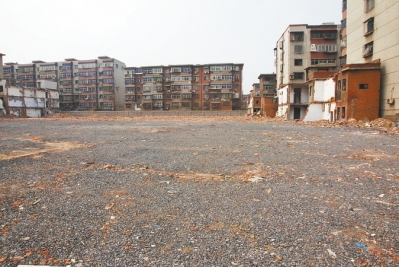 為降塵，旮旯王村拆遷后裸露的地面上鋪了一層石子。