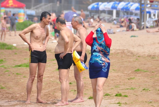 2013年7月3日，山東青島青島高溫來襲，“青島大媽”不懼滸苔，戴著“強盜面具”出現(xiàn)在海水浴場消暑降