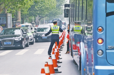 省人民醫(yī)院南門的路中間擺放反光錐，交警示意由西向東車輛從前方繞行。