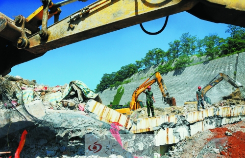 為確保道路盡早通車，工人師傅冒著烈日，指揮施工機械清理爆破現場