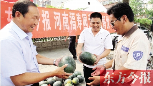 河南福壽園區域總經理吳正宗（左一）、東方今報發行中心副總監王路喜（中）在街頭給市民送瓜