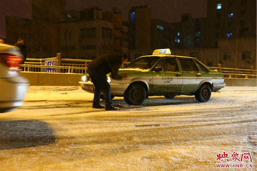 一位出租車(chē)司機(jī)在車(chē)輪前灑上雪，希望能增加輪胎的摩擦力。