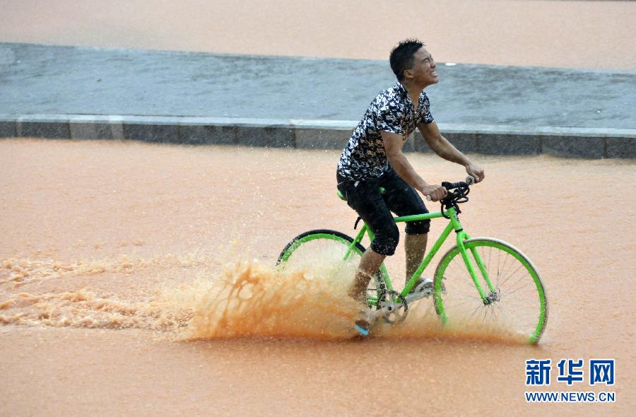 5月11日，一名行人在深圳街頭冒雨騎行。