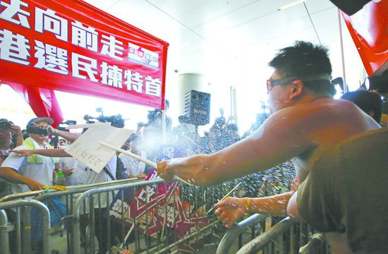 17日，在香港立法會外，一名反對政改的男子向支持派人群投擲標牌。