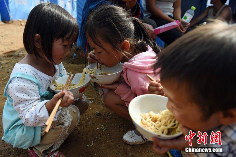 2014年8月6日，云南魯?shù)辇堫^山災(zāi)區(qū)，兒童在帳篷外吃飯。