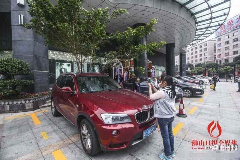 一輛停在停車位上的寶馬轎車，被墜落的樹枝砸中，樹枝徑直插入車內，現場引發不少市民圍觀拍照。